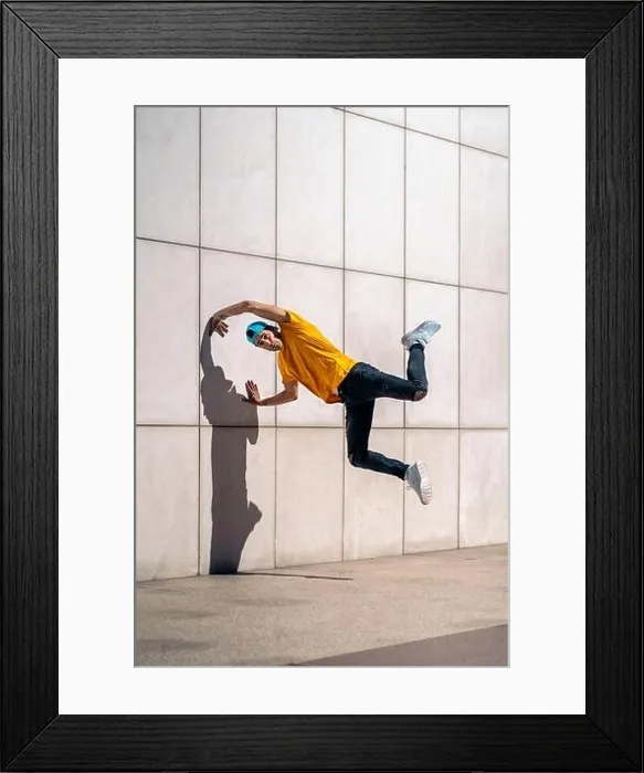 Framed Print : Confident young boy doing break dance dances against white wall in the street Framed Print : Confident young boy doing break dance dances against white wall in the street