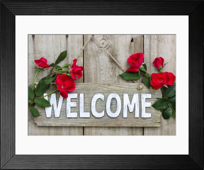 Framed Print : Weathered wood welcome sign hanging on wooden door with flower border of red roses Framed Print : Weathered wood welcome sign hanging on wooden door with flower border of red roses