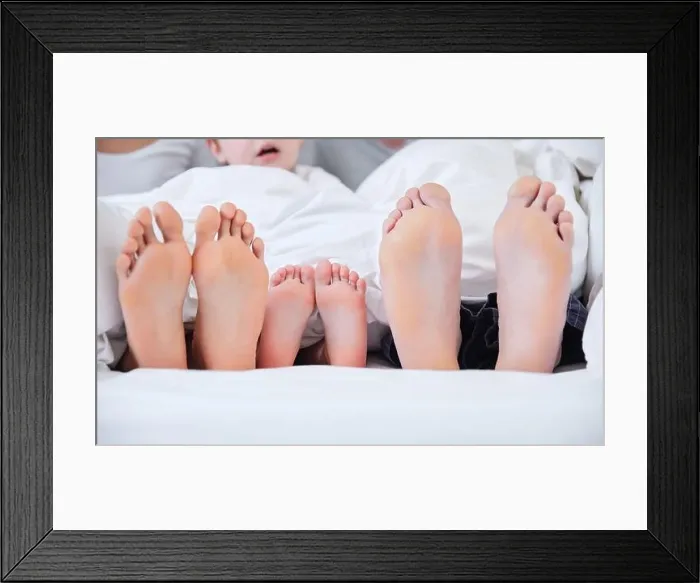 Framed Print : Family resting day. Shot of an unrecognizable family laying barefoot on a bed at home Framed Print : Family resting day. Shot of an unrecognizable family laying barefoot on a bed at home