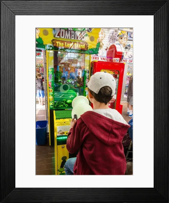 Framed Print : A young boy plays a video game in an amusements arcade Framed Print : A young boy plays a video game in an amusements arcade