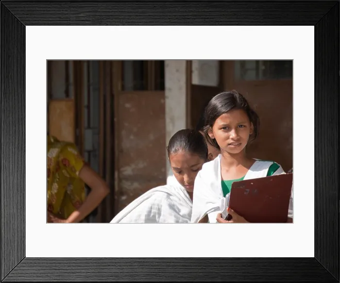 Framed Print : School girl in a Bangladeshi village, holding a board, with friend in the background Framed Print : School girl in a Bangladeshi village, holding a board, with friend in the background