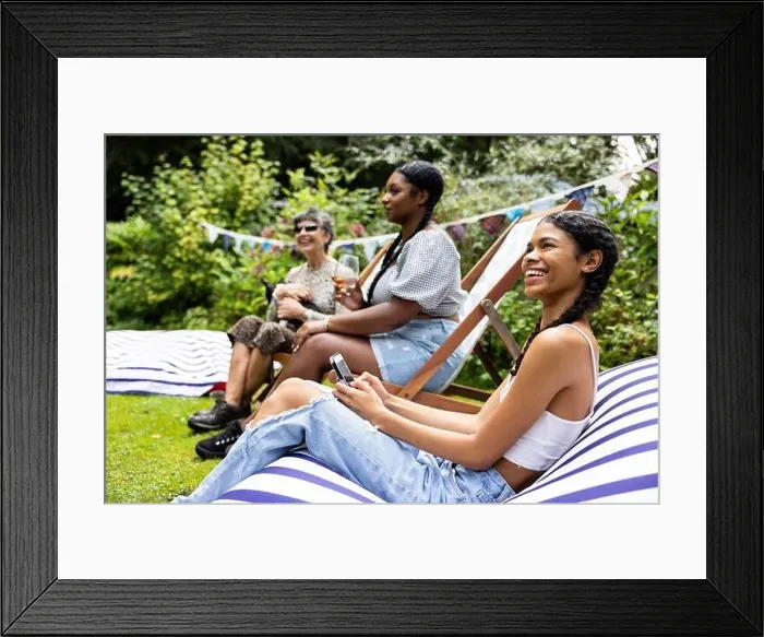 Framed Print : Mixed group of female friends and family gathering to have fun and enjoy a summer BBQ garden party