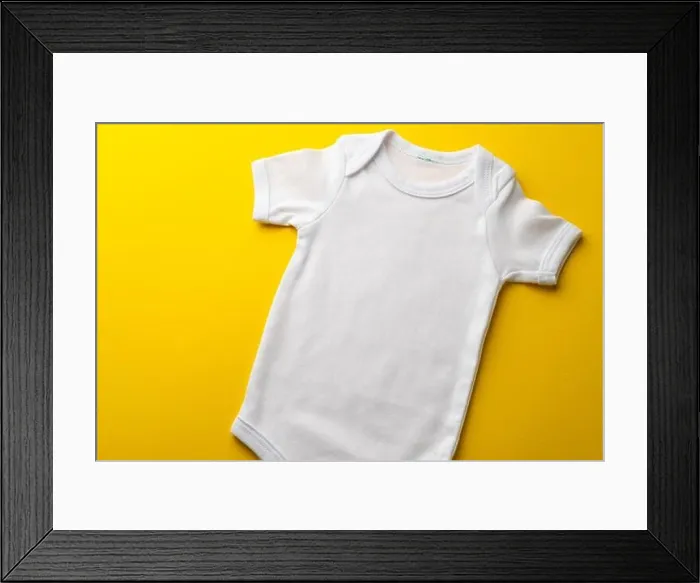 Framed Print : Close up of baby white t shirt with copy space on yellow background Framed Print : Close up of baby white t shirt with copy space on yellow background