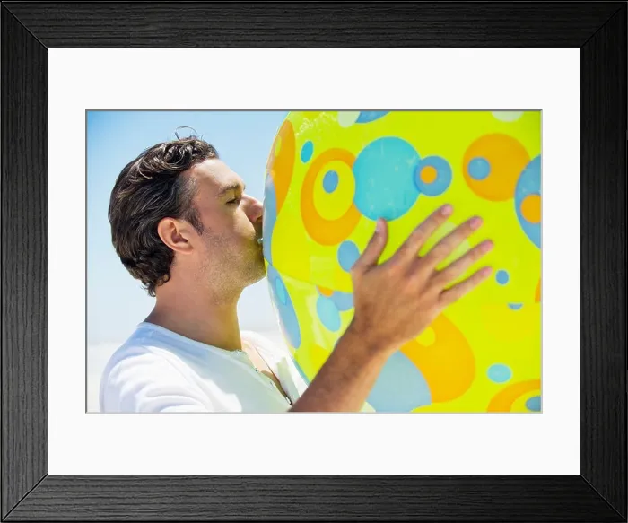 Framed Print : Side profile of a man blowing beach ball