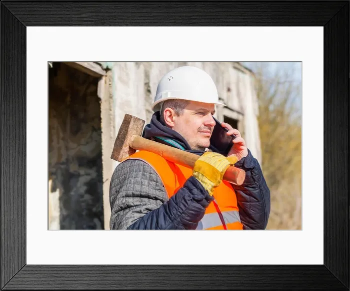 Framed Print : Worker with sledge hammer talking on cell phone Framed Print : Worker with sledge hammer talking on cell phone