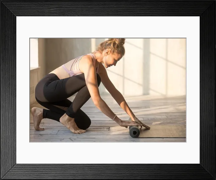 Framed Print : Young female unrolling yoga mat is preparing for session Framed Print : Young female unrolling yoga mat is preparing for session