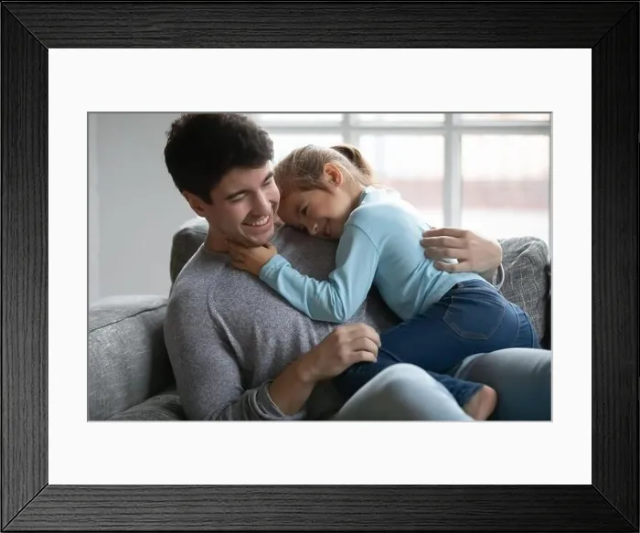 Framed Print : Close up happy father and little daughter cuddling on couch Framed Print : Close up happy father and little daughter cuddling on couch