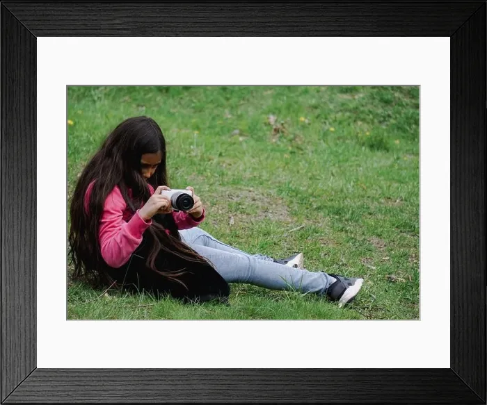 Framed Print : A girl sitting on theme meadow while looking at the camera