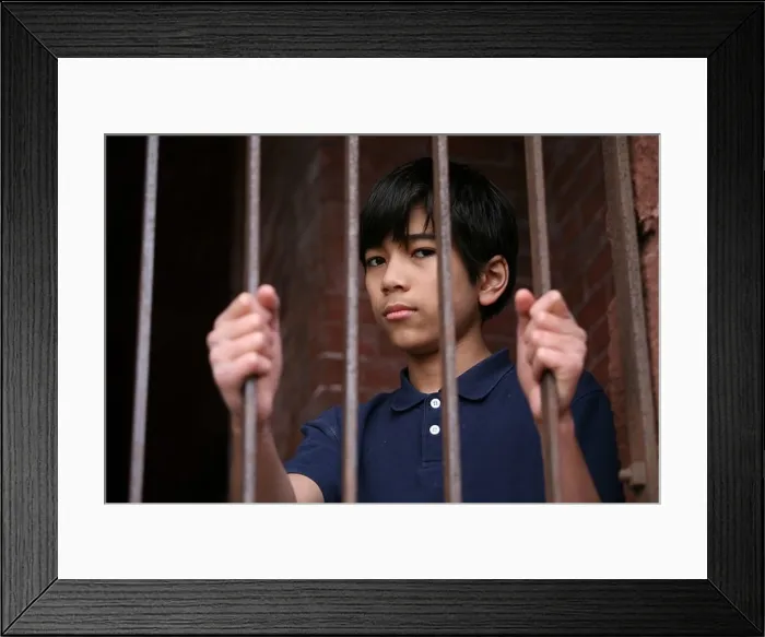 Framed Print : Boy standing behind bars Framed Print : Boy standing behind bars
