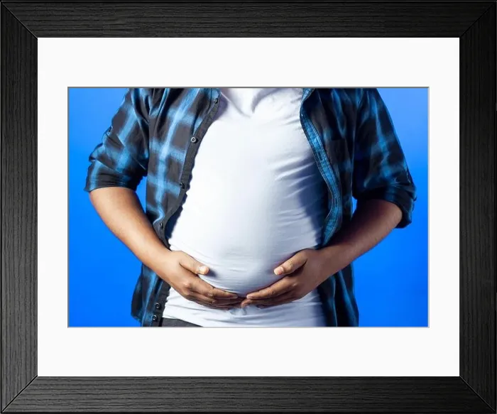 Framed Print : portrait of an Indian guy showing his fat on the stomach, isolated on blue background Framed Print : portrait of an Indian guy showing his fat on the stomach, isolated on blue background