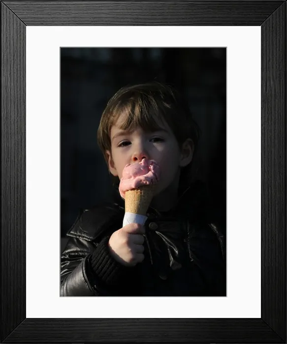 Framed Print : An Italian girl enjoys the first days of spring licking an ice cream cone outside. Spilimbergo, Italy