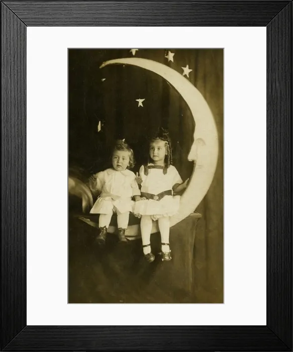 Framed Print : Circa 1910 photograph of a young boy and girl sitting on a paper moon. Studio photograph Framed Print : Circa 1910 photograph of a young boy and girl sitting on a paper moon. Studio photograph