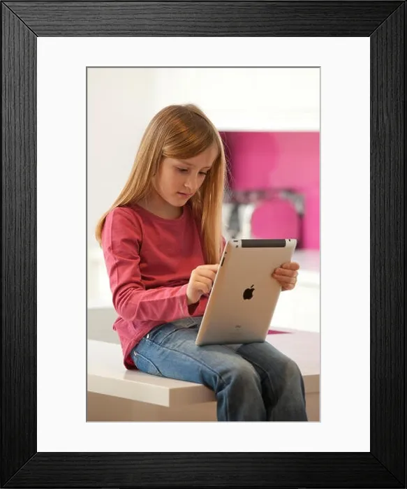 Framed Print : Young girl playing on an apple iPad tablet computer Framed Print : Young girl playing on an apple iPad tablet computer