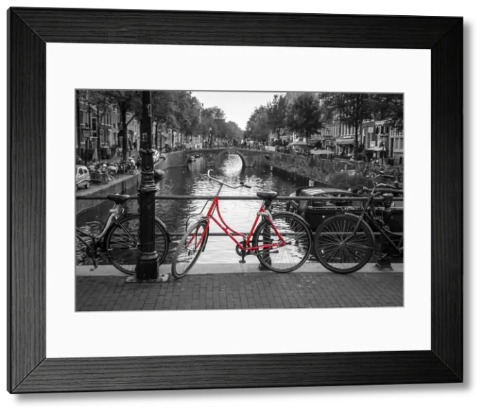Framed Print : A picture of a red bike on the bridge over the channel in Amsterdam. The background is black and white Framed Print : A picture of a red bike on the bridge over the channel in Amsterdam. The background is black and white
