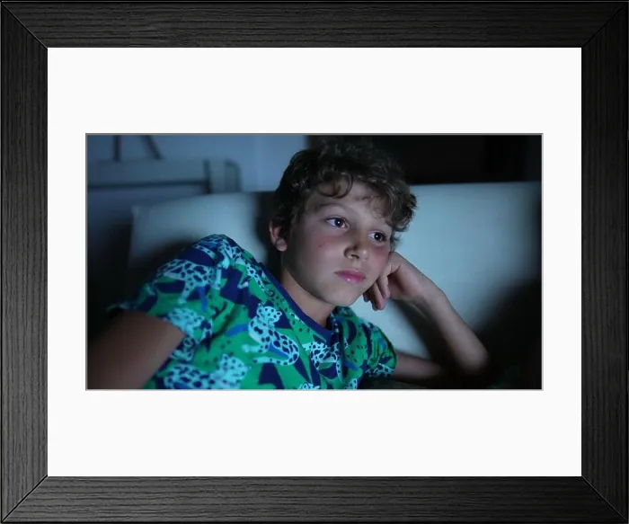 Framed Print : Young boy staring at movie entertainment at night Framed Print : Young boy staring at movie entertainment at night