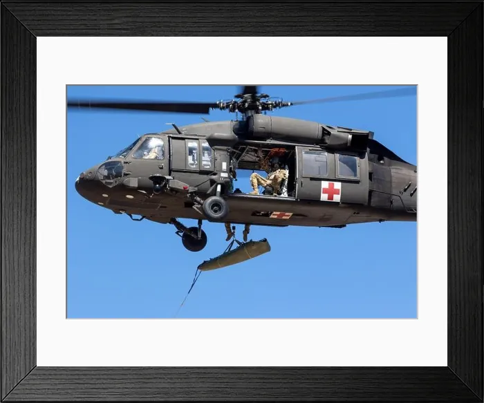 Framed Print : An aircrew assigned to U.S. Army Air Ambulance Detachment- Yakima Training Center conducts a hoist of a simulated SKED litter patient with members of Framed Print : An aircrew assigned to U.S. Army Air Ambulance Detachment- Yakima Training Center conducts a hoist of a simulated SKED litter patient with members of