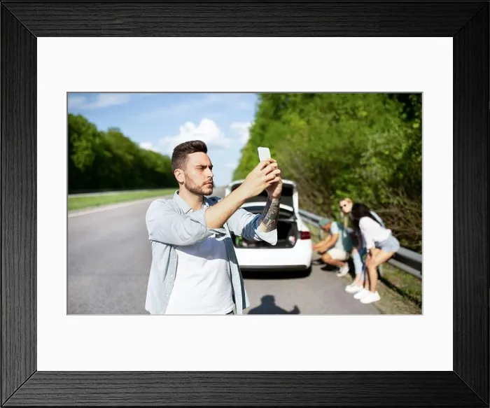 Framed Print : Young guy standing on road next to broken car, looking for mobile network signal, trying to call roadside assistance Framed Print : Young guy standing on road next to broken car, looking for mobile network signal, trying to call roadside assistance