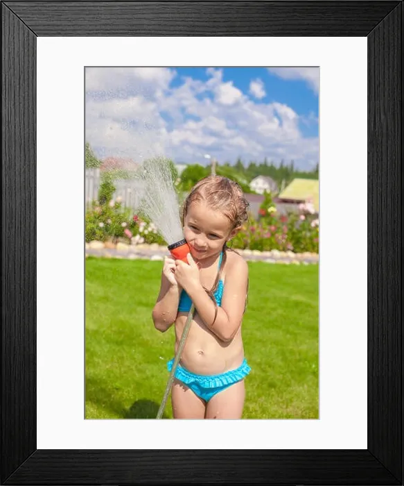 Framed Print : Happy adorable little girl pouring water from a hose and laughing Framed Print : Happy adorable little girl pouring water from a hose and laughing