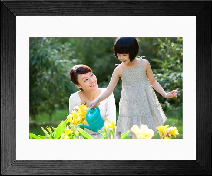 Framed Print : Mother and daughter watering in garden Framed Print : Mother and daughter watering in garden