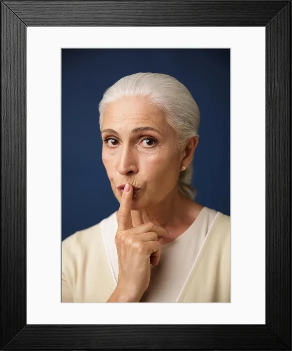 Framed Print : Close-up portrait of beautiful old woman, showing silence gesture, over dark blue background Framed Print : Close-up portrait of beautiful old woman, showing silence gesture, over dark blue background