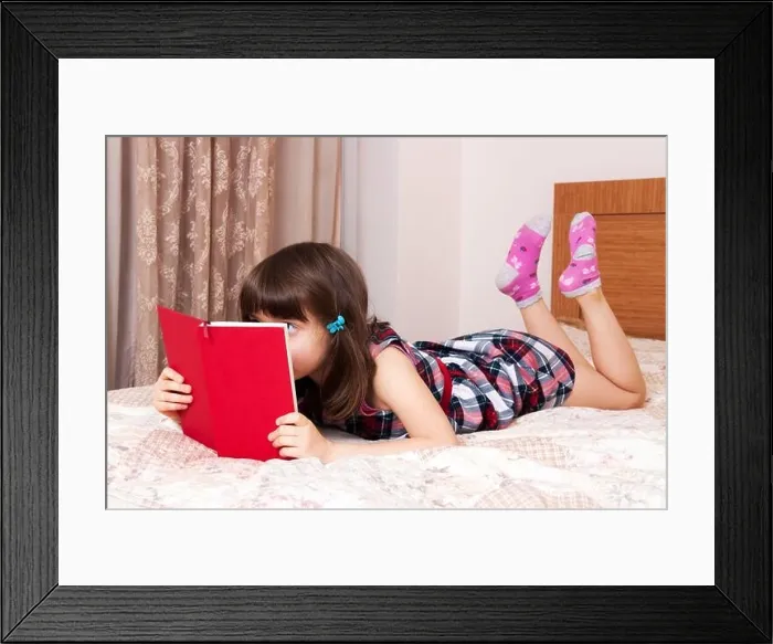 Framed Print : Little girl reading a book at home Framed Print : Little girl reading a book at home