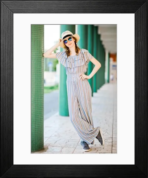 Framed Print : Young teenaged girl in jumpsuit dress posing at colonnade with green pillars, front view Framed Print : Young teenaged girl in jumpsuit dress posing at colonnade with green pillars, front view