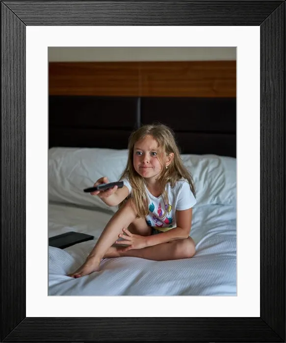 Framed Print : baby on the bed with a remote control Framed Print : baby on the bed with a remote control