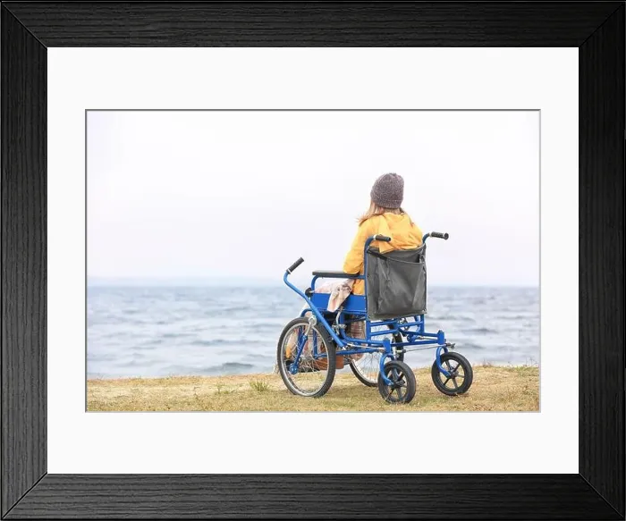 Framed Print : Cute girl in wheelchair on sea shore Framed Print : Cute girl in wheelchair on sea shore