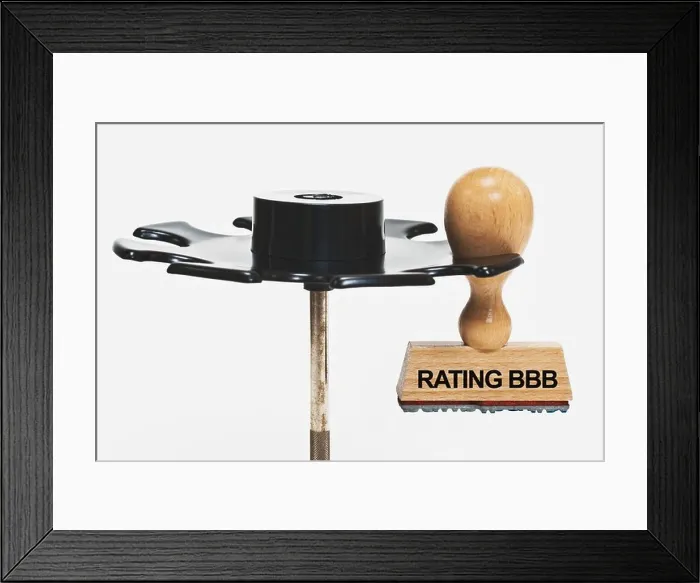 Framed Print : one stamp hangs in a stamp rack, he has the inscription Rating BBB, background white Framed Print : one stamp hangs in a stamp rack, he has the inscription Rating BBB, background white