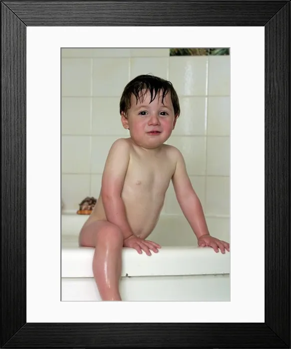 Framed Print : Young boy standing smiling in a bath looking naughty Framed Print : Young boy standing smiling in a bath looking naughty