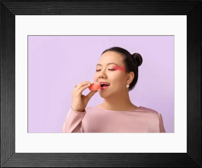 Framed Print : Beautiful Asian woman eating tasty Japanese mochi on color background Framed Print : Beautiful Asian woman eating tasty Japanese mochi on color background