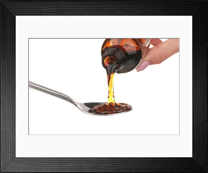 Framed Print : Pouring cough syrup into spoon on white background Framed Print : Pouring cough syrup into spoon on white background