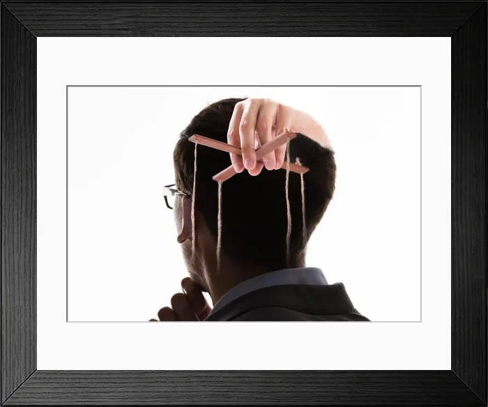 Framed Print : A Businessman's Hand Manipulating Marionette With String Against White Background Framed Print : A Businessman's Hand Manipulating Marionette With String Against White Background