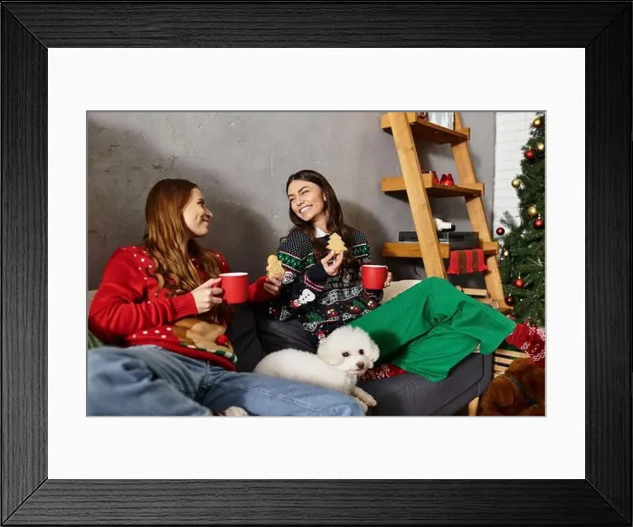 Framed Print : Two friends enjoy Christmas treats with their adorable Bichon Frise while relaxing in festive attire at home Framed Print : Two friends enjoy Christmas treats with their adorable Bichon Frise while relaxing in festive attire at home