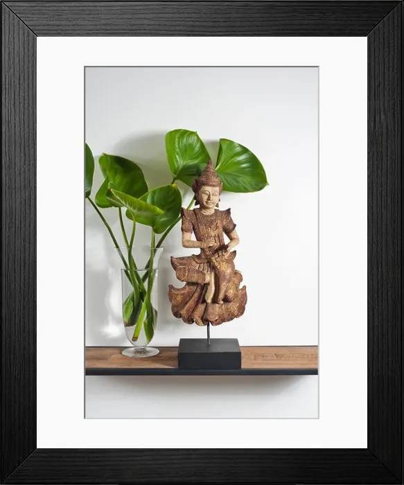 Framed Print : Buddha sculpture with green leafe decoration on side board Framed Print : Buddha sculpture with green leafe decoration on side board
