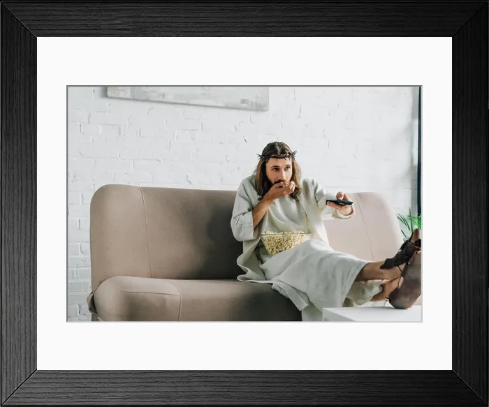 Framed Print : selective focus of Jesus in crown of thorns watching tv and eating popcorn on sofa at home Framed Print : selective focus of Jesus in crown of thorns watching tv and eating popcorn on sofa at home