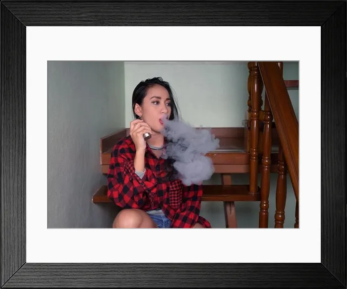 Framed Print : Young beautiful Asian woman vaping at home Framed Print : Young beautiful Asian woman vaping at home