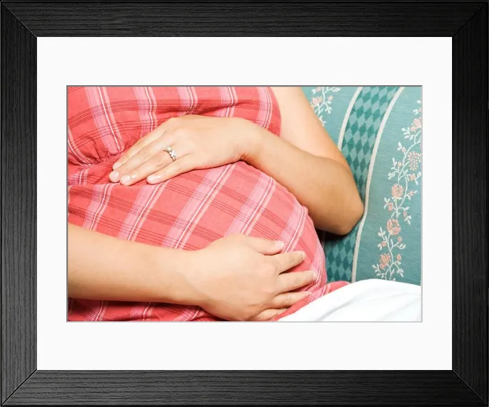 Framed Print : A pregnant woman sitting down on a sofa Framed Print : A pregnant woman sitting down on a sofa