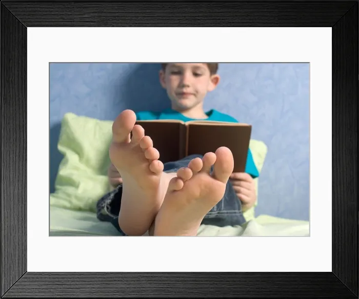 Framed Print : Boy (12-13) reading book on bed Framed Print : Boy (12-13) reading book on bed