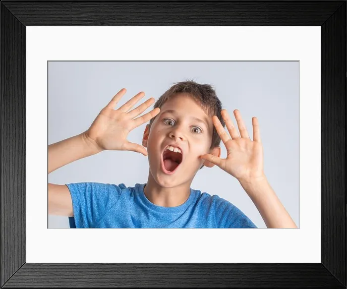 Framed Print : Portrait of shocked surprised boy with opening mouth and rised hands looking direct to the camera Framed Print : Portrait of shocked surprised boy with opening mouth and rised hands looking direct to the camera