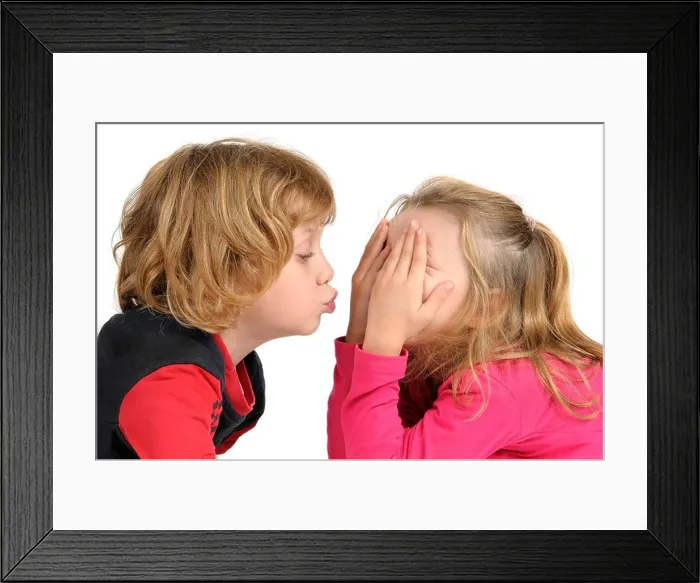Framed Print : Young boy trying to kiss a girl isolated in white Framed Print : Young boy trying to kiss a girl isolated in white