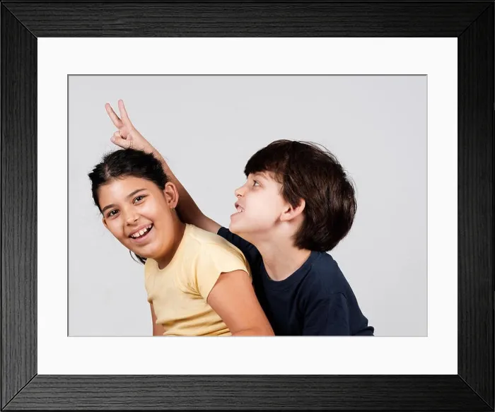 Framed Print : Young boy and girl playing, young boy holding up fingers as rabbit ears Framed Print : Young boy and girl playing, young boy holding up fingers as rabbit ears