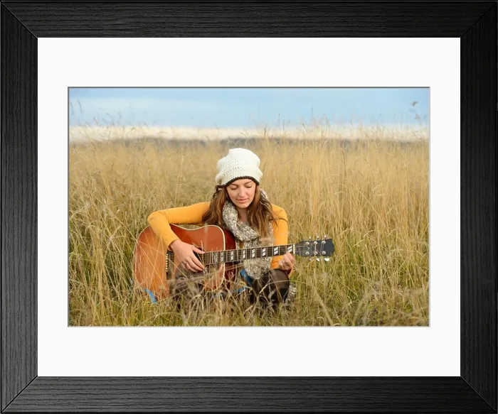 Framed Print : Young woman playing guitar in field Framed Print : Young woman playing guitar in field
