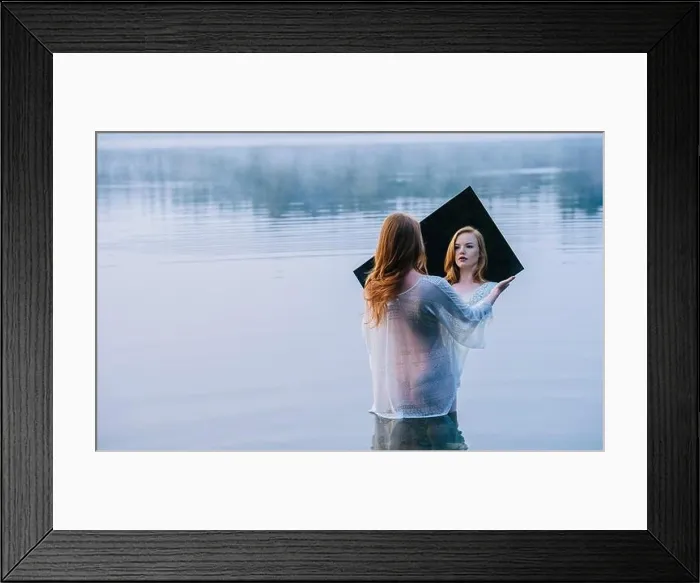 Framed Print : Rear view of young woman standing in lake holding mirror looking at reflection Framed Print : Rear view of young woman standing in lake holding mirror looking at reflection