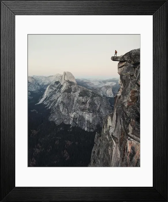 Framed Print : A fearless hiker is standing on an overhanging rock enjoying the view towards famous Half Dome at Glacier Point in