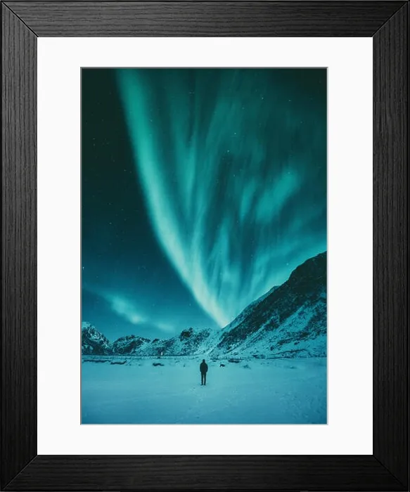 Framed Print : Young man is standing on a remote beach watching the Northern Lights dance above mountains in winter Framed Print : Young man is standing on a remote beach watching the Northern Lights dance above mountains in winter