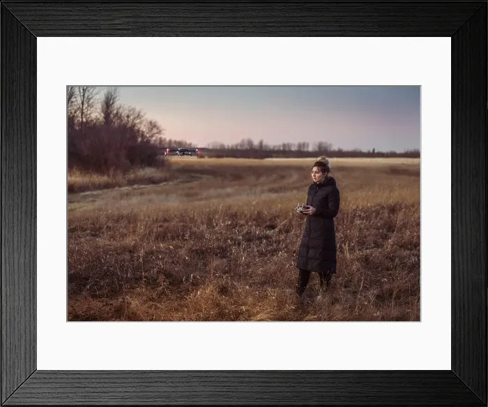 Framed Print : Female drone pilot looks at drone while operating in a field during autumn at dusk Framed Print : Female drone pilot looks at drone while operating in a field during autumn at dusk