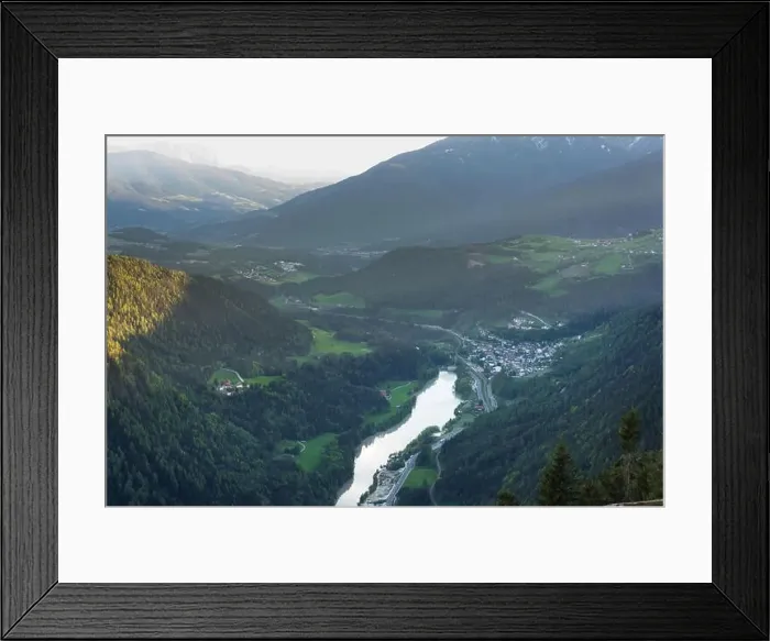 Framed Print : Scenic aerial view on villages in Dolomites with mountains in clouds on background and meadows on foreground Framed Print : Scenic aerial view on villages in Dolomites with mountains in clouds on background and meadows on foreground