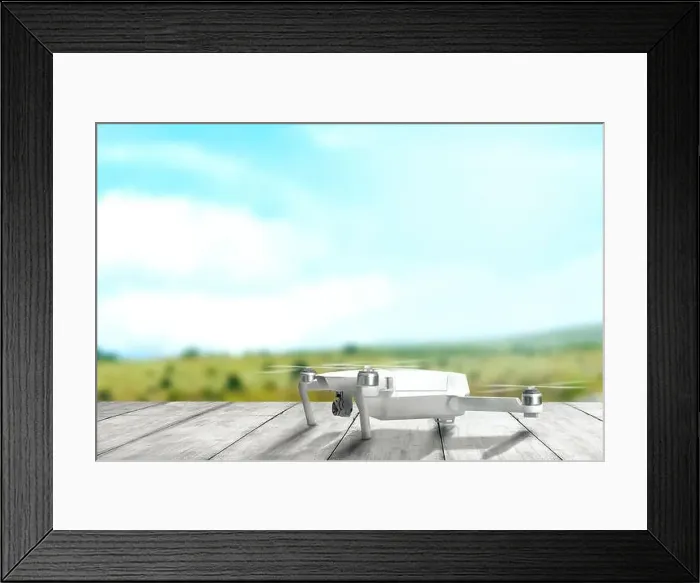Framed Print : White drone with camera on wooden table ready to flying to the air with blurry landscapes background Framed Print : White drone with camera on wooden table ready to flying to the air with blurry landscapes background