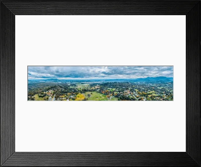 Framed Print : Wide aerial panorama of scenic rural landscape with houses surrounded by forest and mountains Framed Print : Wide aerial panorama of scenic rural landscape with houses surrounded by forest and mountains